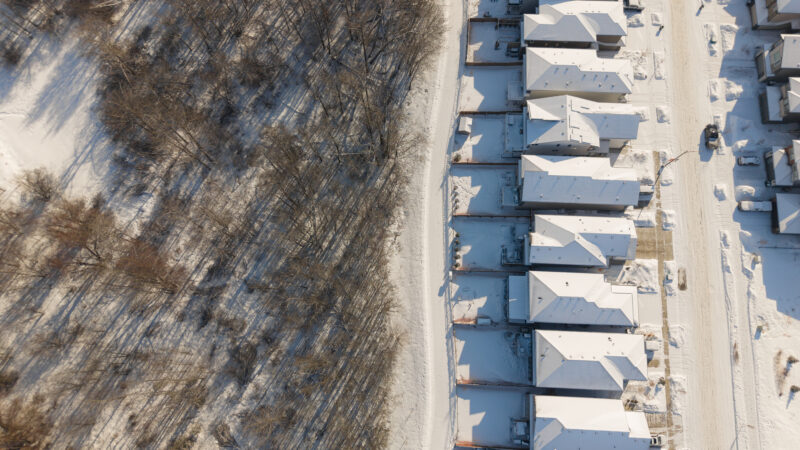 Top down aerial of homes beside a winter forest boundary in Kinglet by Big Lake, Edmonton, Alberta.